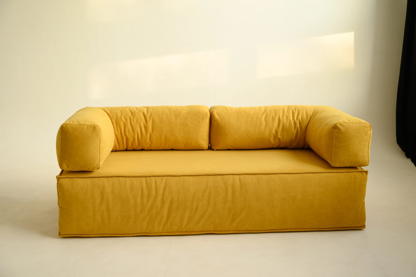 Желтый двухместный диван крупным планом на фоне стены